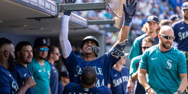 Seattle Mariners' Julio Rodriguez is congratulated by Carlos Santana in the dugout after hitting a solo home run during the eighth inning of a baseball game against the Washington Nationals, Wednesday, Aug. 24, 2022, in Seattle.