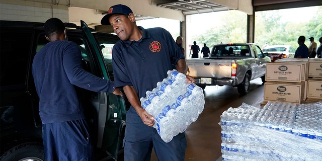 A Jackson, Miss., Fire Department firefighter puts cases of bottled water in a resident's SUV, Aug. 18, 2022, as part of the city's response to longstanding water system problems.