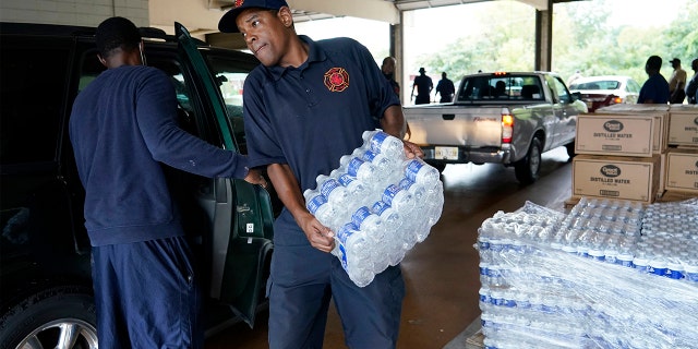 A Jackson, Miss., Fire Department firefighter puts cases of bottled water in a resident's SUV, Aug. 18, 2022, as part of the city's response to longstanding water system problems.