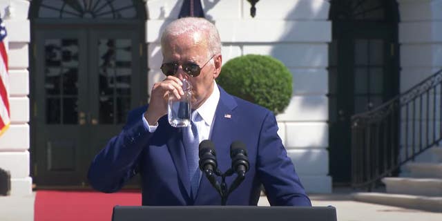 President Joe Biden drinks a glass of water during a speech.