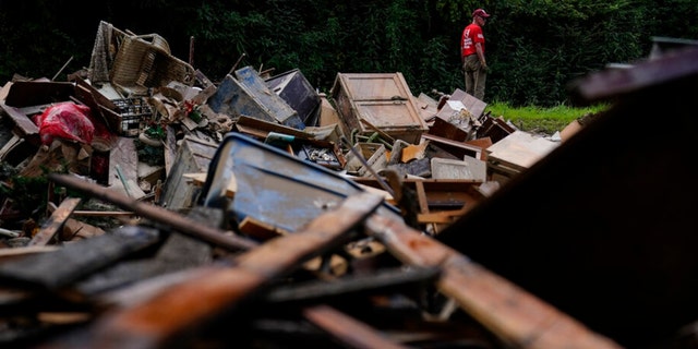 A man stands near a pile of debris as residents start to clean up and rebuild in Fleming-Neon, Kentucky, on Aug. 5, 2022, after massive flooding the previous week.