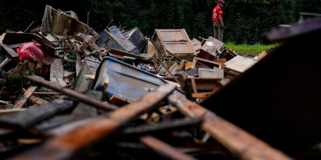 A man stands near a pile of debris as residents start to clean up and rebuild in Fleming-Neon, Kentucky, on Aug. 5, 2022, after massive flooding the previous week.