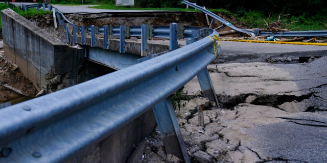 The road leading to a bridge above a creek cracks and breaks after massive flooding on Thursday, Aug. 4, 2022, in Chavies, Kentucky.