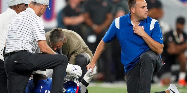 A trainer checks on New York Giants defensive end Kavon Thibodeau after suffering an injury during the first half of a preseason NFL football game against the Cincinnati Bengals on Sunday, Aug. 21, 2022 in East Rutherford, N.J.