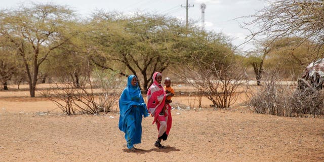 Women walk toward an open-air market in the village of Wagala, northern Kenya, Friday, August 19, 2022. 