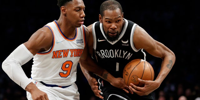 Kevin Durant, #7 of the Brooklyn Nets, dribbles as RJ Barrett, #9 of the New York Knicks, defends during the first half at Barclays Center on March 13, 2022 in the Brooklyn borough of New York City.