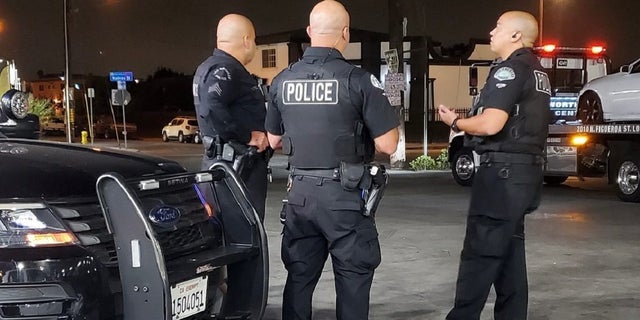 Uniformed LAPD officers standing by cruiser