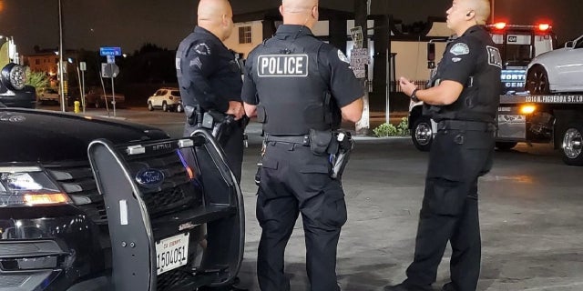 Uniformed LAPD officers standing by cruiser