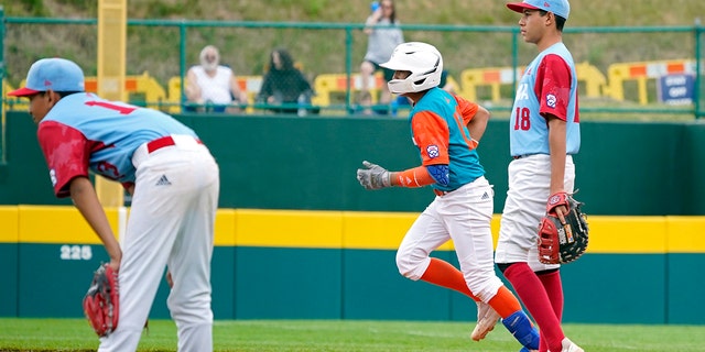 Nicaragua's Luis Garcia, center rounds the bases past Panama first baseman Max Pinzon, #18, on his three run home run off of pitcher Gabriel de Gracia, left, during the fourth inning of a baseball game at the Little League World Series tournament in South Williamsport, Pennsylvania, Tuesday, Aug. 23, 2022.