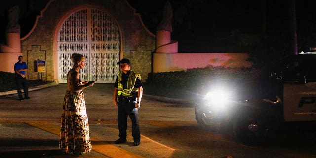 A police officer speaks with a woman outside former President Donald Trump's Mar-a-Lago home after it was raided, in Palm Beach, Florida, Aug. 8, 2022.