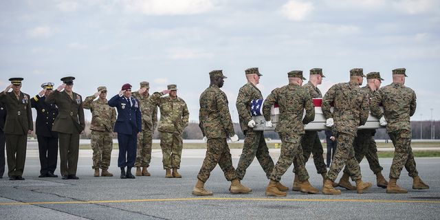 Military officials salute as a U.S. Marine Corps carry team carries the transfer case containing the remains of Marine Cpl. Jacob Moore, of Catlettsburg, Kentucky, during a dignified transfer at Dover Air Force Base March 25, 2022 in Dover, Delaware. 