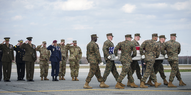 Military officials salute as a U.S. Marine Corps carry team carries the transfer case containing the remains of Marine Cpl. Jacob Moore, of Catlettsburg, Kentucky, during a dignified transfer at Dover Air Force Base March 25, 2022 in Dover, Delaware. 