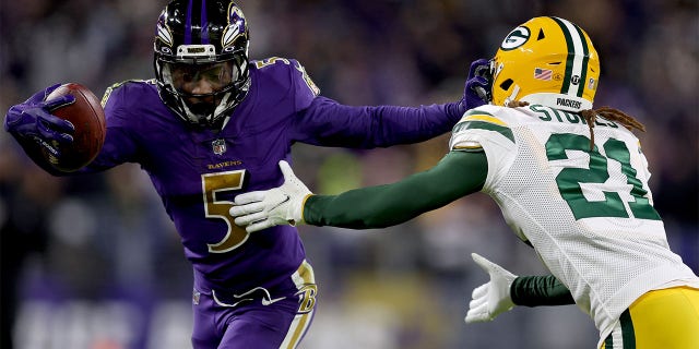 Marquise Brown #5 of the Baltimore Ravens runs with the ball after the catch against Eric Stokes #21 of the Green Bay Packers in the fourth quarter at M&T Bank Stadium on December 19, 2021 in Baltimore, Maryland.