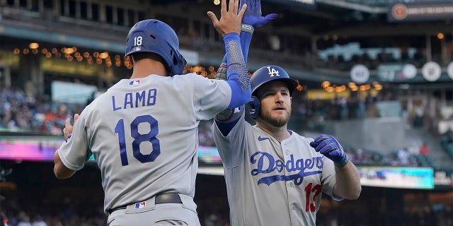 Los Angeles Dodgers' Max Muncy, right, celebrates after hitting a two-run home run that scored Jake Lamb (18) during the second inning of a baseball game against the San Francisco Giants in San Francisco, Monday, Aug. 1, 2022.