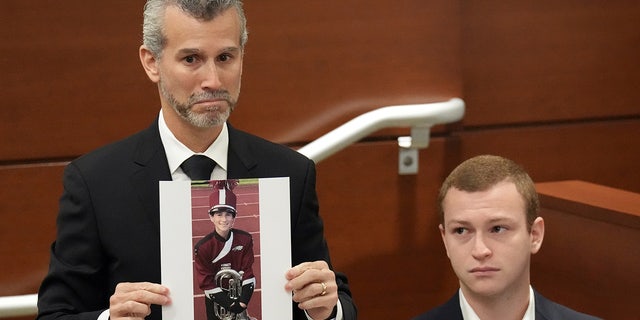 Max Schachter, with his son, 瑞安, 在他身边, holds a photograph of his other son, 亚历克斯, just before giving his victim impact statement during the penalty phase of the trial of Marjory Stoneman Douglas High School shooter Nikolas Cruz at the Broward County Courthouse in Fort Lauderdale, 佛罗里达.