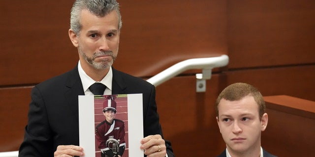 Max Schachter, with his son, Ryan, by his side, holds a photograph of his other son, Alex, just before giving his victim impact statement during the penalty phase of the trial of Marjory Stoneman Douglas High School shooter Nikolas Cruz at the Broward County Courthouse in Fort Lauderdale, Florida.