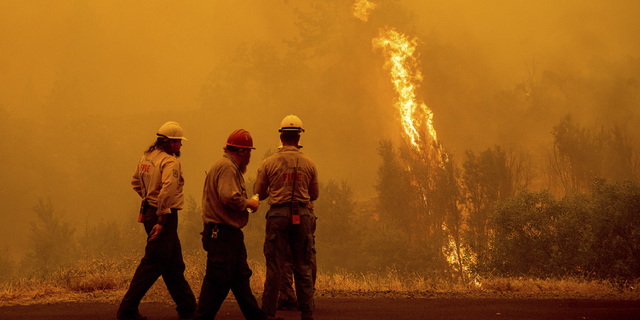 Flames from the McKinney Fire burn beyond firefighters in Klamath National Forest, Calif., on Sunday, July 31.