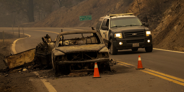 The charred remnants of a car towing a trailer that burned when the McKinney Fire jumped the Klamath River remain on a highway in the Klamath National Forest northwest of Yreka, Calif., on July 31