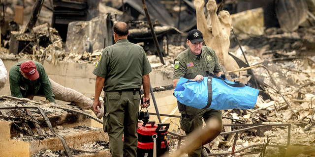 A sheriff's deputy carries remains of a McKinney Fire victim from a destroyed home on Monday, Aug. 1, in the Klamath National Forest in California.