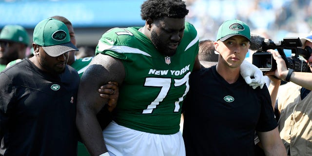 Mekhi Becton #77 of the New York Jets is helped off the field after being injured during the third quarter against the Carolina Panthers at Bank of America Stadium on Sept. 12, 2021 in Charlotte, North Carolina. 