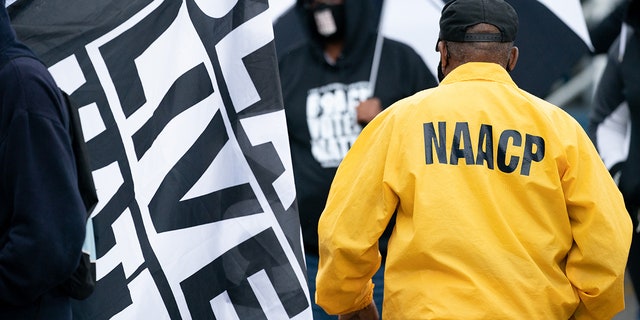 FILE: A man wearing a NAACP jacket walks between demonstrators before a protest march on April 24, 2021, in Elizabeth City, North Carolina. 
