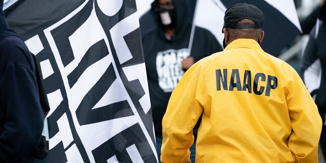 FILE: A man wearing a NAACP jacket walks between demonstrators before a protest march on April 24, 2021, in Elizabeth City, North Carolina. 