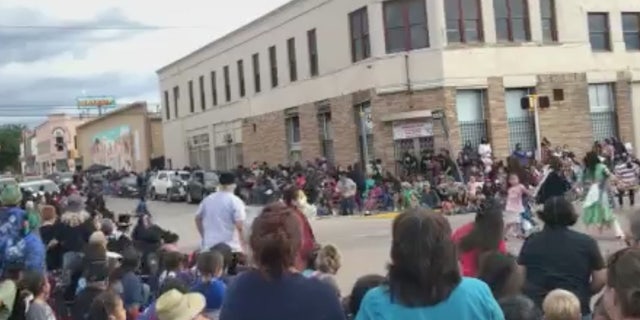 A crowd reacts and flees in terror as an SUV speeds through a parade in New Mexico on Thursday.
