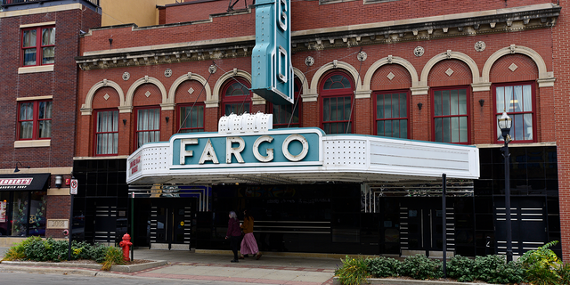 Pedestrians pass in front of the Fargo Theatre temporary closed due to the Coronavirus in downtown Fargo, North Dakota, U.S., on Thursday, Oct. 15, 2020.