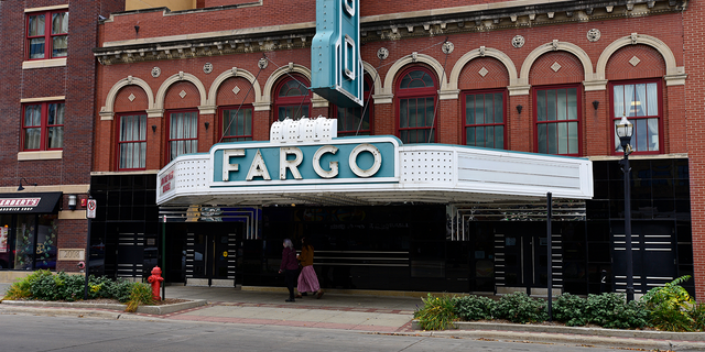 Pedestrians pass in front of the Fargo Theatre temporary closed due to the Coronavirus in downtown Fargo, North Dakota, U.S., on Thursday, Oct. 15, 2020.