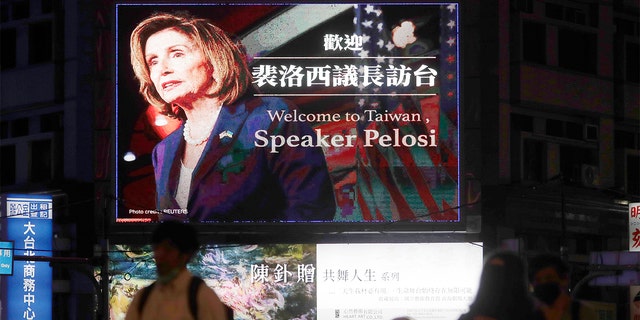 People walk past a sign welcoming House Speaker Nancy Pelosi in Taipei, Taiwan, Tuesday, August 2, 2022.