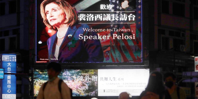 People walk past a billboard welcoming U.S. House Speaker Nancy Pelosi, in Taipei, Taiwan, Tuesday, Aug 2, 2022.