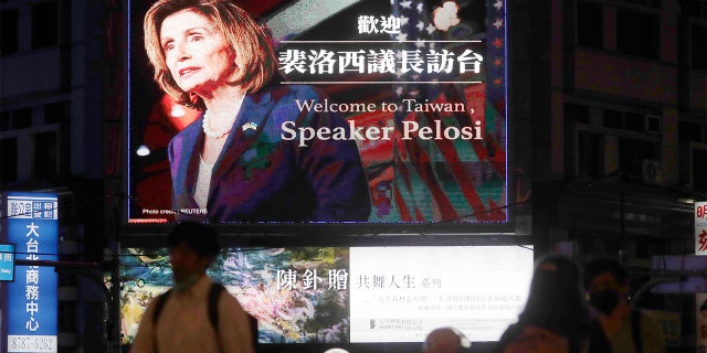 People walk past a sign welcoming House Speaker Nancy Pelosi in Taipei, Taiwan, Tuesday, August 2, 2022.