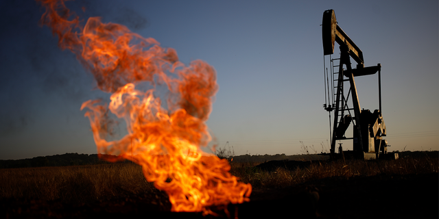 A natural gas flare burns near an oil pump jack at the New Harmony Oil Field in Grayville, Illinois, US, on Sunday, June 19, 2022.