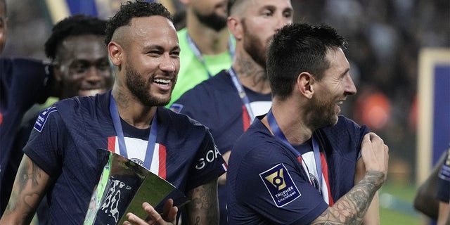PSG's Neymar, left, holds the trophy as he celebrate with his teammate Lionel Messi after winning the French Super Cup final soccer match between Nantes and Paris Saint-Germain at Bloomfield Stadium in Tel Aviv, Israel, Sunday, July 31, 2022. PSG won 4-0. 
