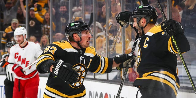 Patrice Bergeron, right, of the Bruins reacts with Brad Marchand after scoring against the Carolina Hurricanes during the Stanley Cup playoffs on May 8, 2022, in Boston.