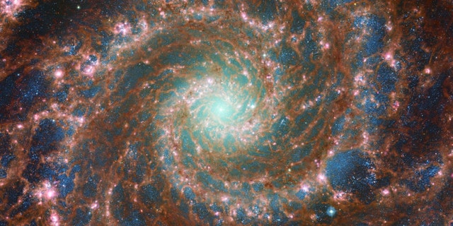 M74, NASA/ESA Hubble Uzay Teleskobu ve NASA/ESA/CSA James Webb Uzay Teleskobu'ndan alınan verileri içeren bu optik/orta-kızılötesi bileşik görüntüde en parlak şekilde parlıyor.  Bu görüntü, Hubble'ın Araştırmalar için Gelişmiş Kamerası (ACS) ve Web'in çeşitli dalga boylarını yakalayan güçlü Orta Kızılötesi (MIRI) aracı sayesinde inanılmaz bir derinliğe sahiptir. 