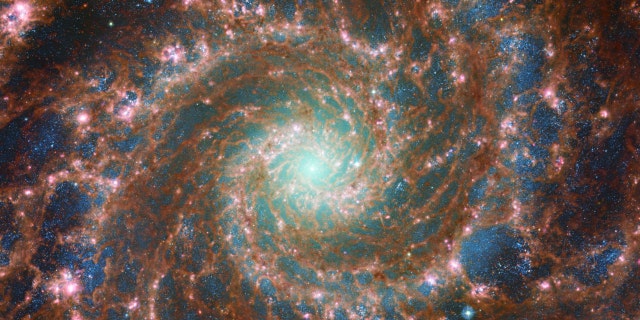 M74 błyszczy najjaśniej na tym złożonym obrazie optycznym/podczerwonym, który zawiera dane z Kosmicznego Teleskopu Hubble'a NASA/ESA i Kosmicznego Teleskopu Jamesa Webba NASA/ESA/CSA.  Ten obraz ma niesamowitą głębię dzięki zaawansowanej kamerze do badań Hubble'a (ACS) i potężnemu instrumencie sieci Web w średniej podczerwieni (MIRI), który rejestruje różne długości fal. 