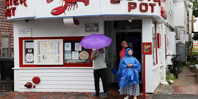 Visitors stand outside of the Lobster Pot in Provincetown after they read the sign posted on the door saying the restaurant would be closed Thursday, Aug. 11. 
