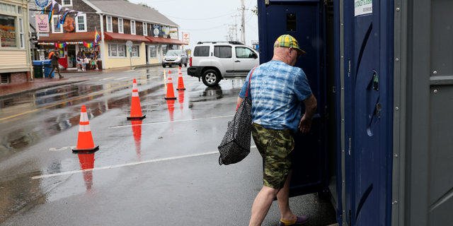 A visitor stops to use a porta-potty installed on Ryder Street in Provincetown, Mass., on Thursday, Aug. 11.