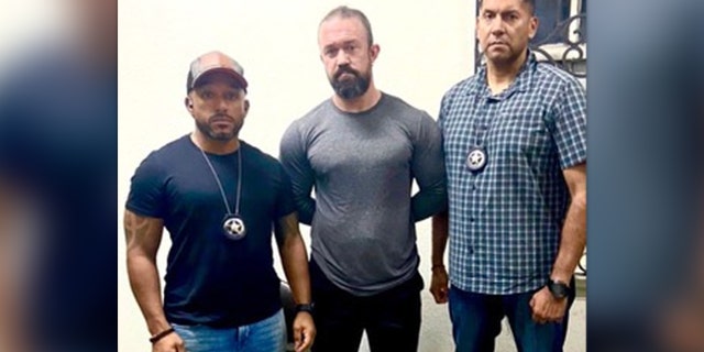 Marshal flanking RJ McLeod after his arrest in Sonsonate, El Salvador, Monday, August 29, 2022.