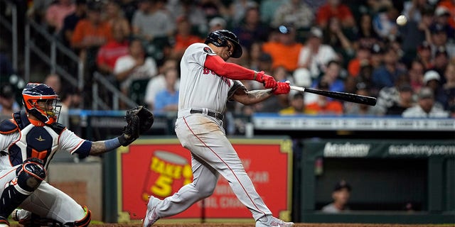 Boston Red Sox's Rafael Devers, right, hits a home run as Houston Astros catcher Martin Maldonado reaches for the pitch during the sixth inning of a baseball game Tuesday, Aug. 2, 2022, in Houston. 