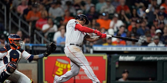 Boston Red Sox's Rafael Devers, right, hits a home run as Houston Astros catcher Martin Maldonado reaches for the pitch during the sixth inning of a baseball game Tuesday, Aug. 2, 2022, in Houston.