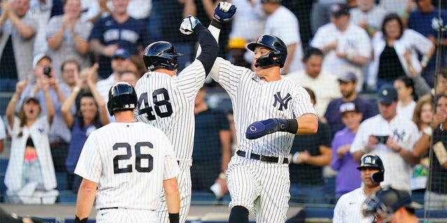 New York Yankees' DJ LeMahieu (26) looks on as Anthony Rizzo (48) celebrates with Aaron Judge after Rizzo hit a three-run home run during the first inning of a baseball game against the Seattle Mariners, Monday, Aug. 1, 2022, in New York. 