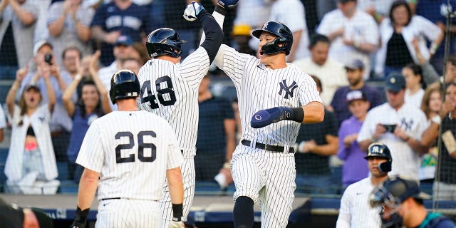 New York Yankees' DJ LeMahieu (26) looks on as Anthony Rizzo (48) celebrates with Aaron Judge after Rizzo hit a three-run home run during the first inning of a baseball game against the Seattle Mariners, Monday, Aug. 1, 2022, in New York.