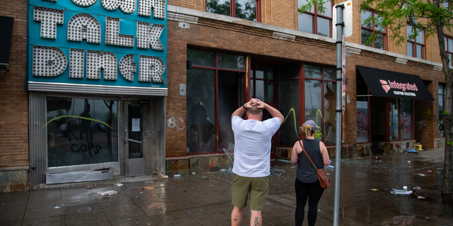 Charles Stotts and wife Kacey White, owners of Town Talk Diner on Lake Street in Minneapolis, watch as water pours out of their restaurant on Thursday, May 28, 2020. The building was looted the night before. "We have our whole lives tied into this restaurant," said Stotts. 