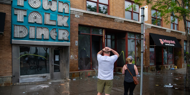 Charles Stotts and wife Kacey White, owners of Town Talk Diner on Lake Street in Minneapolis, watch as water pours out of their restaurant on May 28, 2020. The building had been looted the night before.
