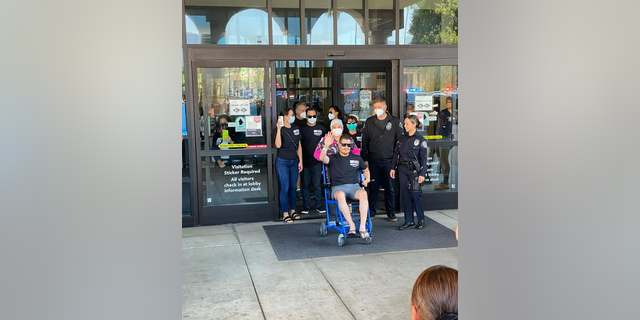 Arcadia Police Officer Kevin Manley waving to supporters as he was wheeled out of Huntington Memorial Hospital in Pasadena on Aug. 18, 2022.