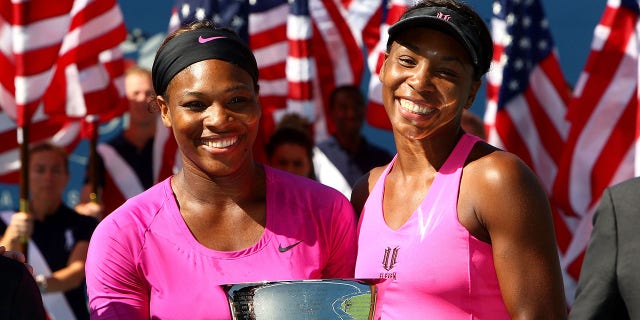 Serena Williams (L) and Venus Williams pose with the championship trophy after defeating Cara Black of Zimbabwe and Liezel Huber in the Women's Doubles final on day fifteen of the 2009 U.S. Open.