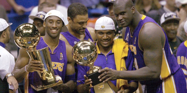 From left to right, Los Angeles Lakers Kobe Bryant, Lindsay Hunter and Shaquille O'Neal hold championship trophies after winning Game 4 of the NBA Finals at The Meadowlands in East Rutherford, New Jersey June 12, 2002.