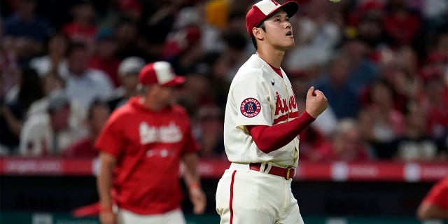 Los Angeles Angels starting pitcher Shohei Ohtani tosses the baseball in the air before being taken out of the game by manager Phil Nevin, background left, during the sixth inning against the Oakland Athletics on Wednesday, Aug. 3, 2022, in Anaheim, Calif.